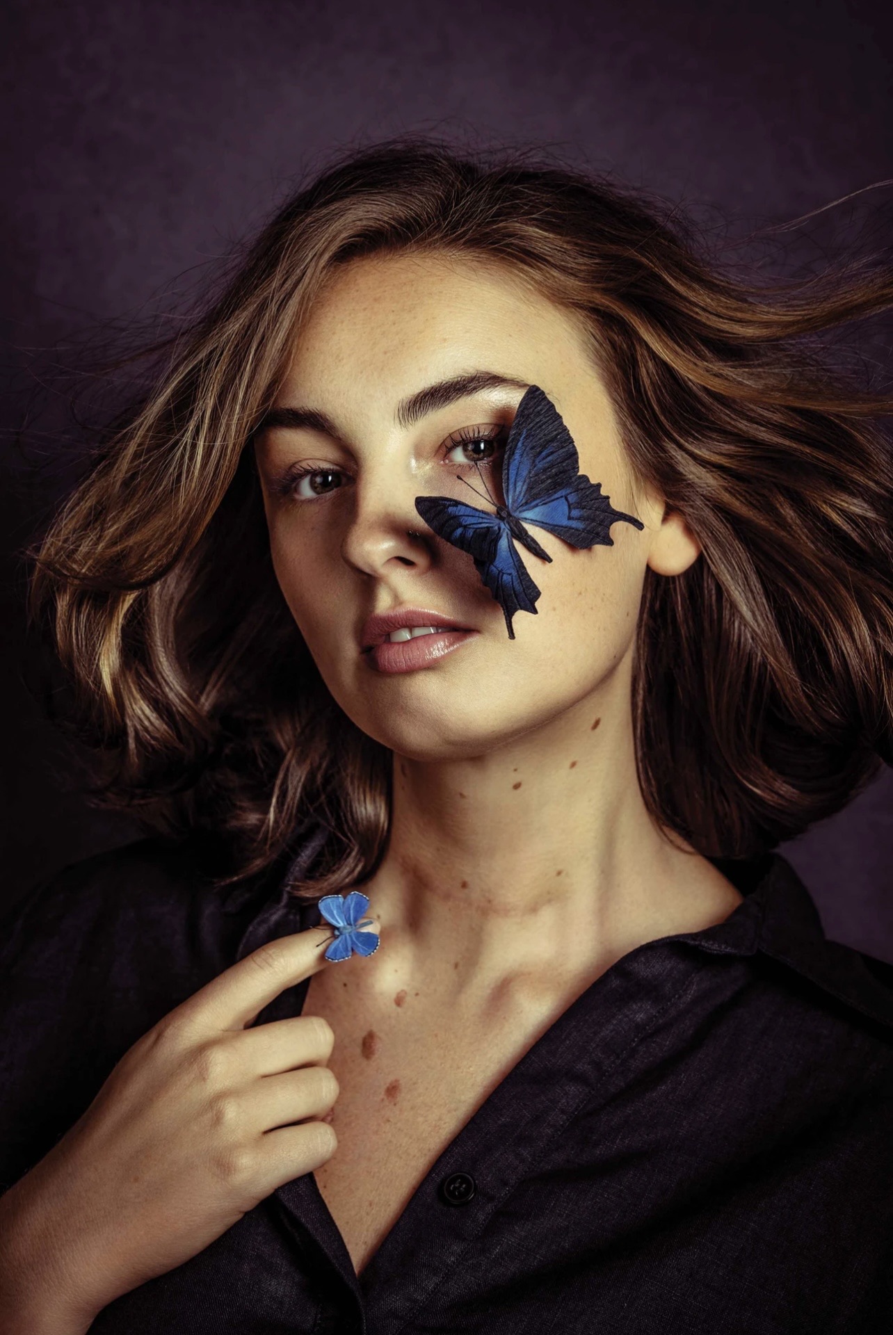 Brunette editorial portrait with glossy sculpted waves and a blue butterfly